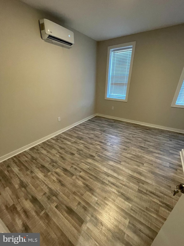 spare room with wood-type flooring and an AC wall unit