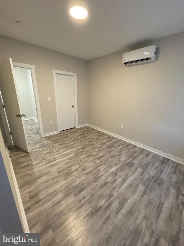 spare room featuring wood-type flooring and an AC wall unit