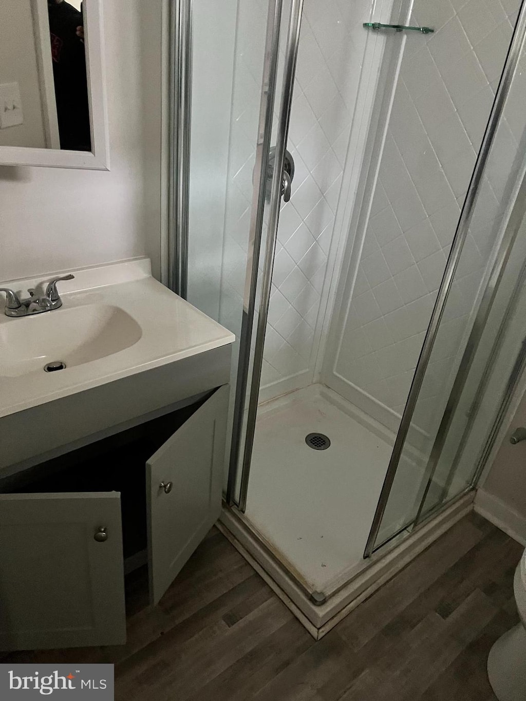 bathroom featuring hardwood / wood-style floors, oversized vanity, toilet, and a shower with door