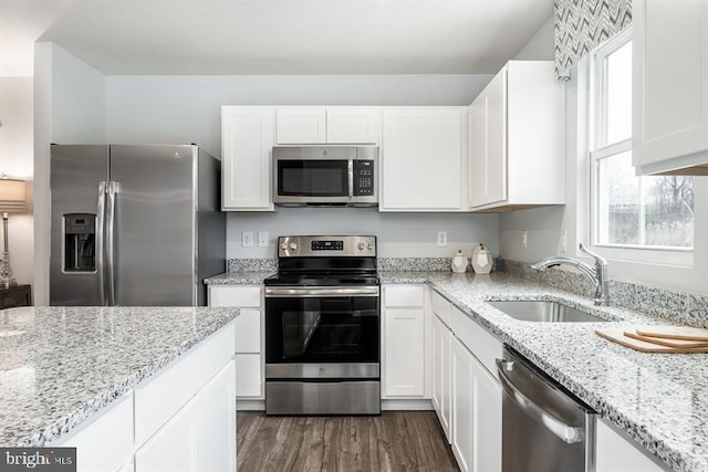 kitchen with plenty of natural light, light stone counters, appliances with stainless steel finishes, and sink