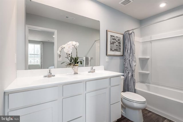 full bathroom with hardwood / wood-style floors, toilet, shower / bath combo with shower curtain, and double sink vanity