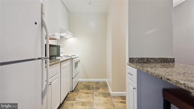 kitchen with white cabinets, light tile floors, light stone countertops, and white appliances