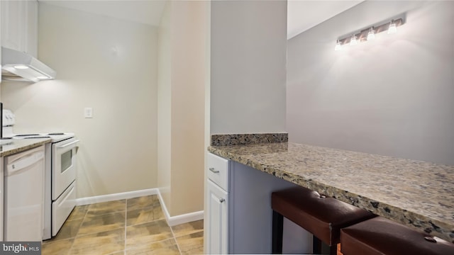 kitchen featuring white appliances, light stone countertops, white cabinetry, and light tile floors