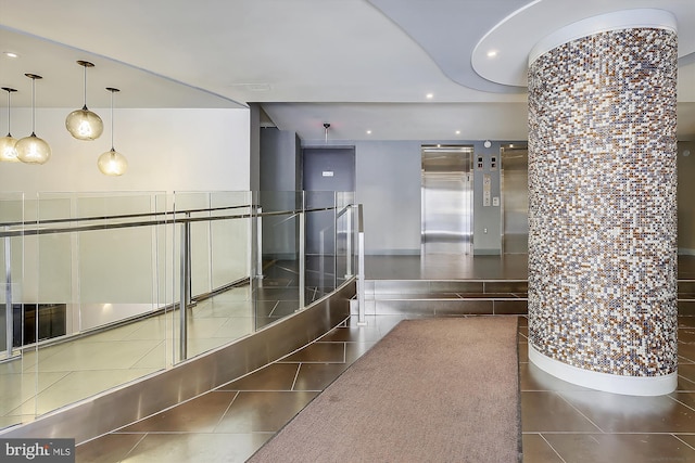 corridor with dark tile flooring and elevator