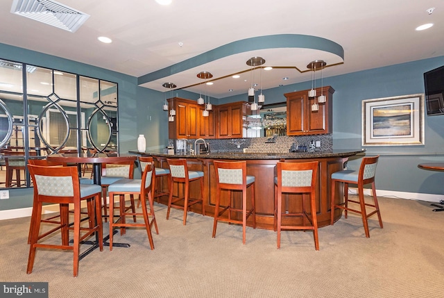 kitchen featuring sink, backsplash, decorative light fixtures, kitchen peninsula, and a kitchen breakfast bar