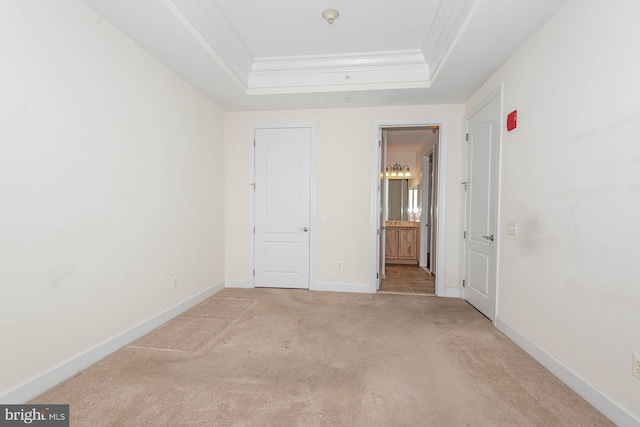 carpeted spare room featuring crown molding and a raised ceiling