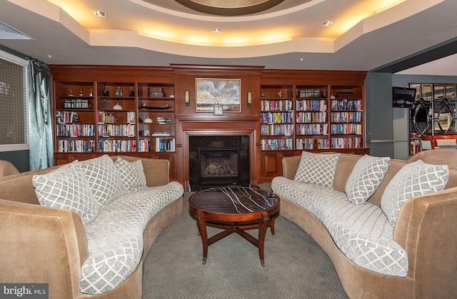 living room with built in features and a raised ceiling