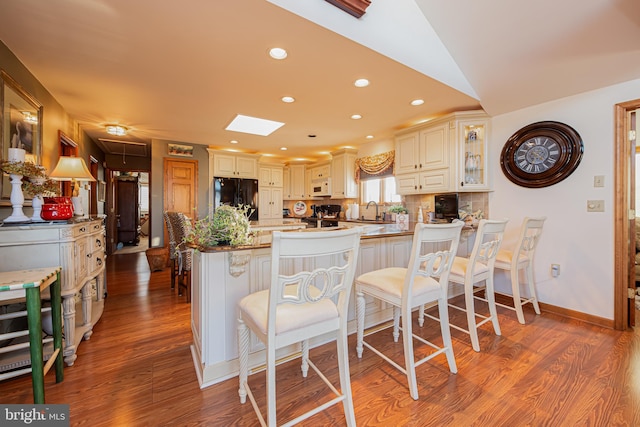 kitchen with black fridge, a kitchen island, a breakfast bar, and wood-type flooring