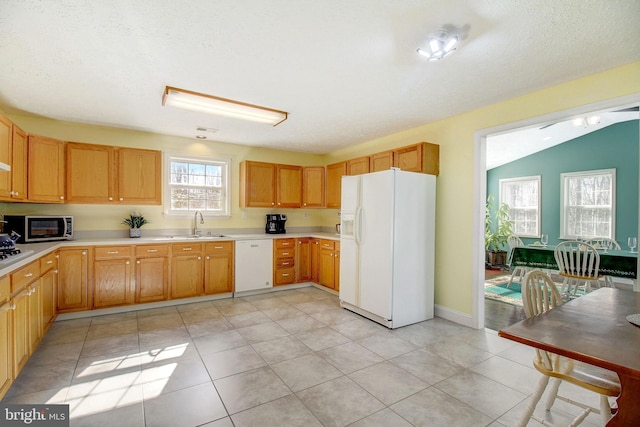 kitchen with lofted ceiling, white appliances, plenty of natural light, and light tile floors