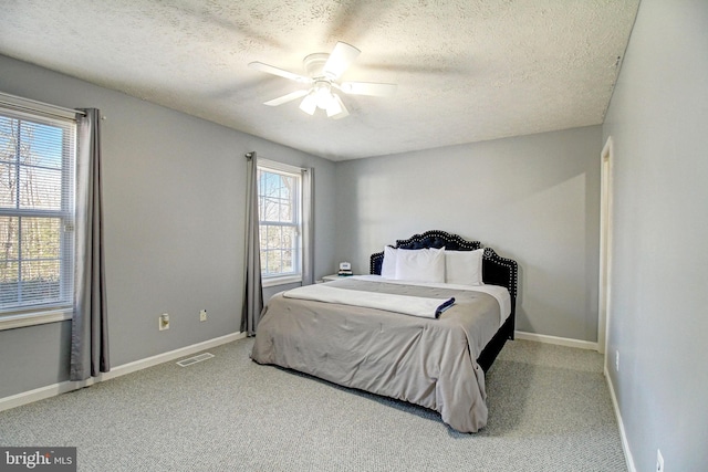 carpeted bedroom with ceiling fan and a textured ceiling