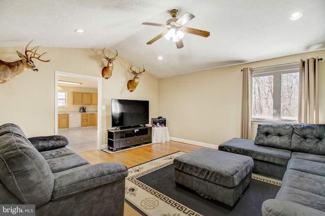 living room with a textured ceiling, light hardwood / wood-style floors, ceiling fan, and vaulted ceiling