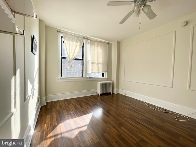 spare room with dark hardwood / wood-style flooring, ceiling fan, and radiator heating unit