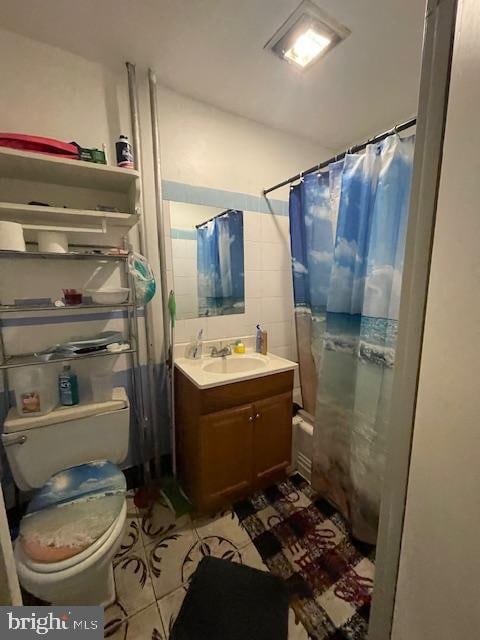 bathroom with tile walls, toilet, tile floors, and vanity with extensive cabinet space