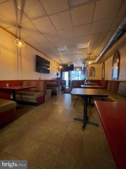 recreation room with a paneled ceiling and tile flooring