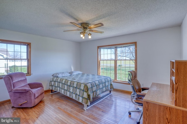 bedroom with ceiling fan, light hardwood / wood-style flooring, and a textured ceiling