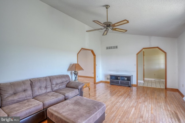 living room featuring ceiling fan, lofted ceiling, light hardwood / wood-style floors, and a textured ceiling