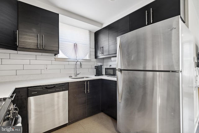 kitchen featuring sink, appliances with stainless steel finishes, tasteful backsplash, and light tile floors