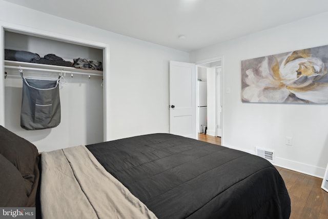 bedroom featuring dark hardwood / wood-style flooring, a closet, and fridge