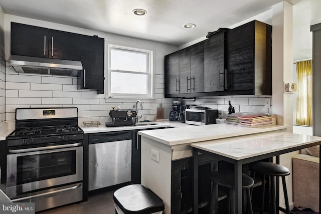 kitchen featuring a breakfast bar, dark tile flooring, tasteful backsplash, stainless steel appliances, and kitchen peninsula