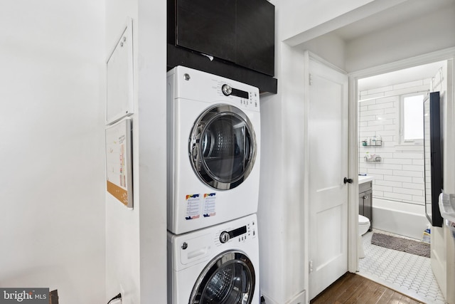 clothes washing area featuring stacked washer / dryer and dark tile floors