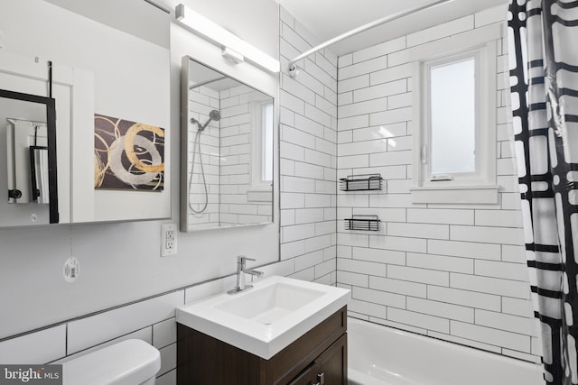 full bathroom featuring vanity, shower / bath combination with curtain, toilet, and tile walls