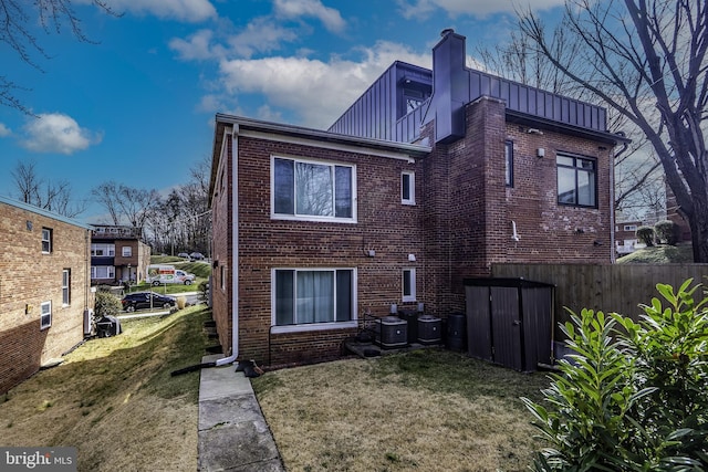 rear view of house featuring central AC and a yard