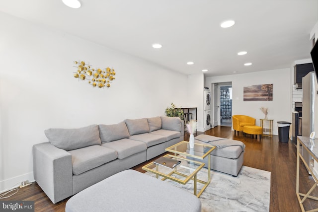 living room featuring dark hardwood / wood-style flooring and stacked washer and dryer