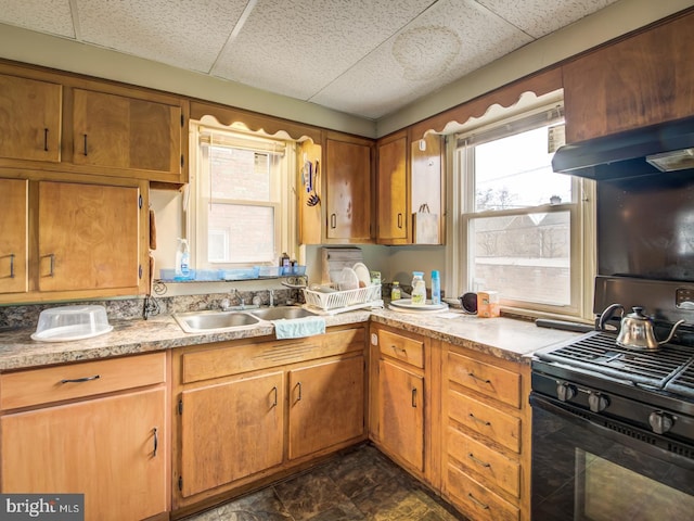 kitchen featuring dark tile floors, sink, black stove, a drop ceiling, and wall chimney range hood