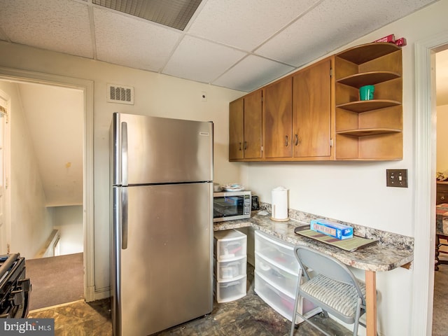 kitchen featuring a paneled ceiling, light stone countertops, dark tile floors, and appliances with stainless steel finishes