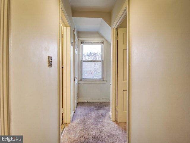 hall featuring vaulted ceiling and light colored carpet