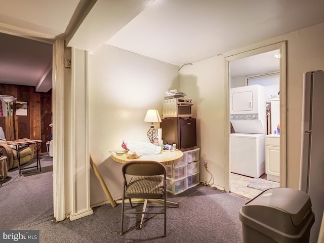 sitting room featuring wood walls, stacked washing maching and dryer, and dark colored carpet