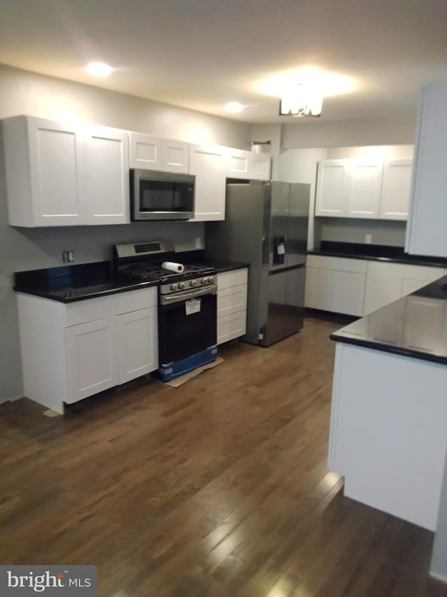 kitchen featuring a notable chandelier, white cabinets, dark wood-type flooring, and stainless steel appliances