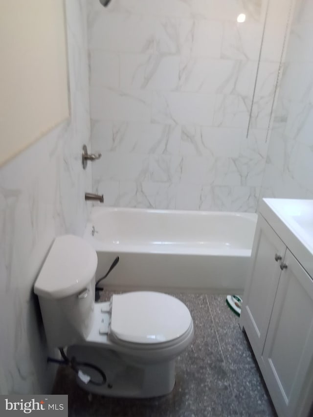 full bathroom featuring tile walls, toilet, tiled shower / bath, tile floors, and vanity