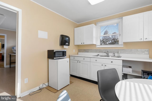 kitchen featuring white cabinets, ornamental molding, sink, and light tile floors