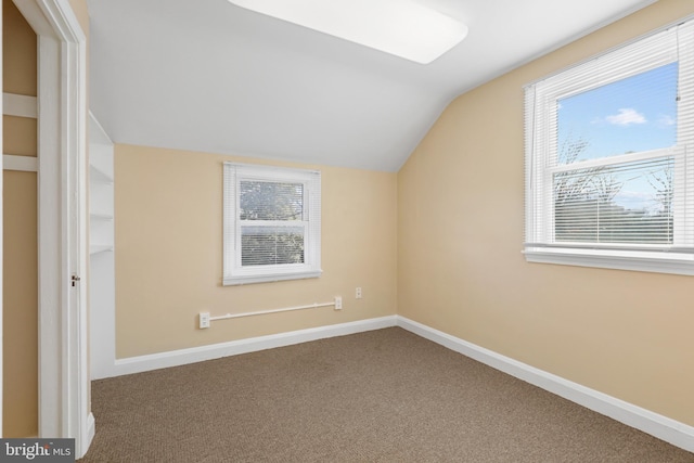 additional living space featuring dark colored carpet and vaulted ceiling