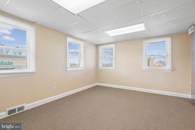 carpeted empty room featuring a paneled ceiling