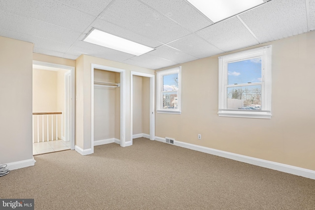 unfurnished bedroom with a drop ceiling and light colored carpet