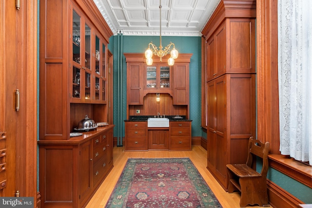 office area with an inviting chandelier, sink, and light wood-type flooring