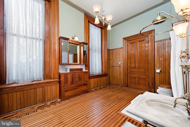 interior space featuring an inviting chandelier, ornamental molding, toilet, and vanity