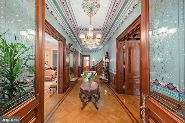 hall with an inviting chandelier, ornamental molding, and light parquet flooring