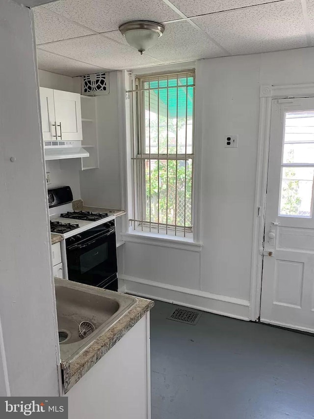 kitchen featuring white cabinets, a drop ceiling, white gas stove, and plenty of natural light