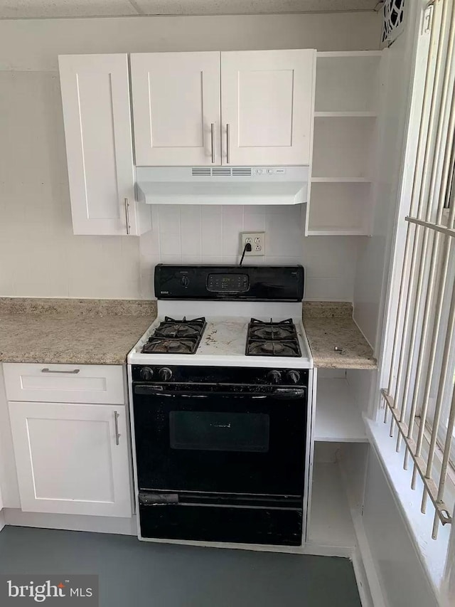 kitchen with white gas range oven, white cabinetry, and light stone countertops