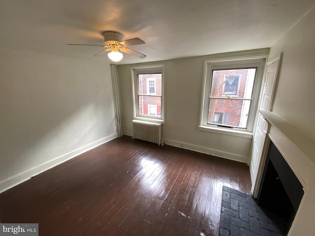 unfurnished room with ceiling fan, radiator heating unit, and dark hardwood / wood-style flooring