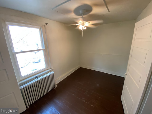 spare room featuring plenty of natural light, dark hardwood / wood-style floors, ceiling fan, and radiator