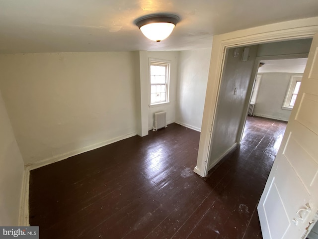 unfurnished room with dark hardwood / wood-style flooring and radiator heating unit