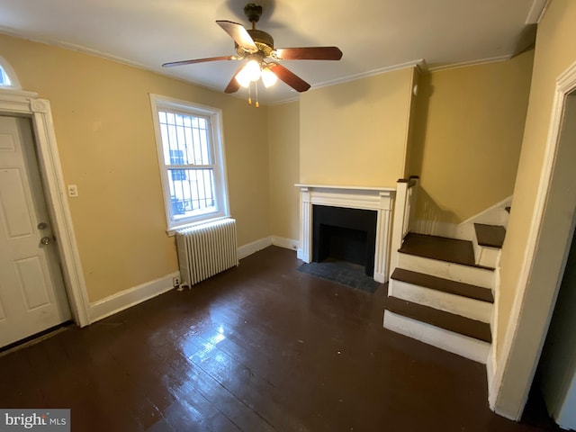 unfurnished living room with ornamental molding, dark hardwood / wood-style flooring, ceiling fan, and radiator heating unit