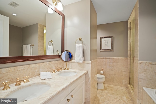 bathroom with double sink, tile walls, a bathing tub, toilet, and oversized vanity