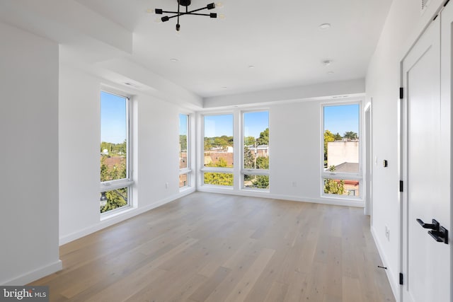 unfurnished room featuring a chandelier and light hardwood / wood-style floors