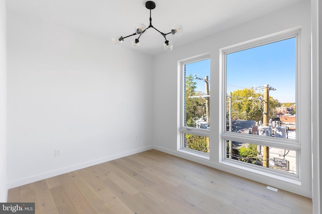 empty room featuring an inviting chandelier and light hardwood / wood-style floors