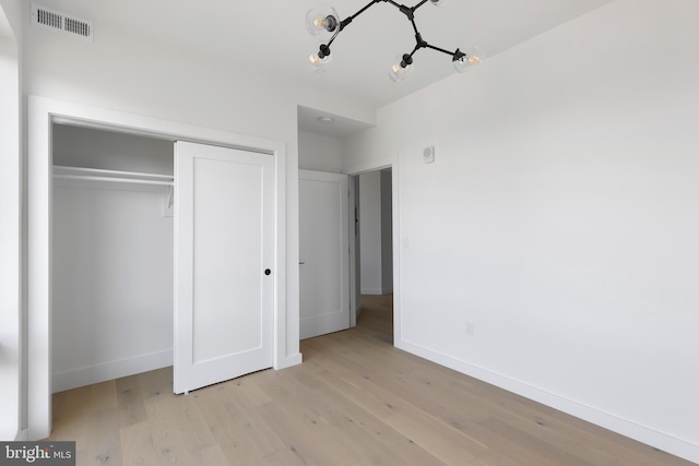 unfurnished bedroom with a closet, a chandelier, and light hardwood / wood-style floors